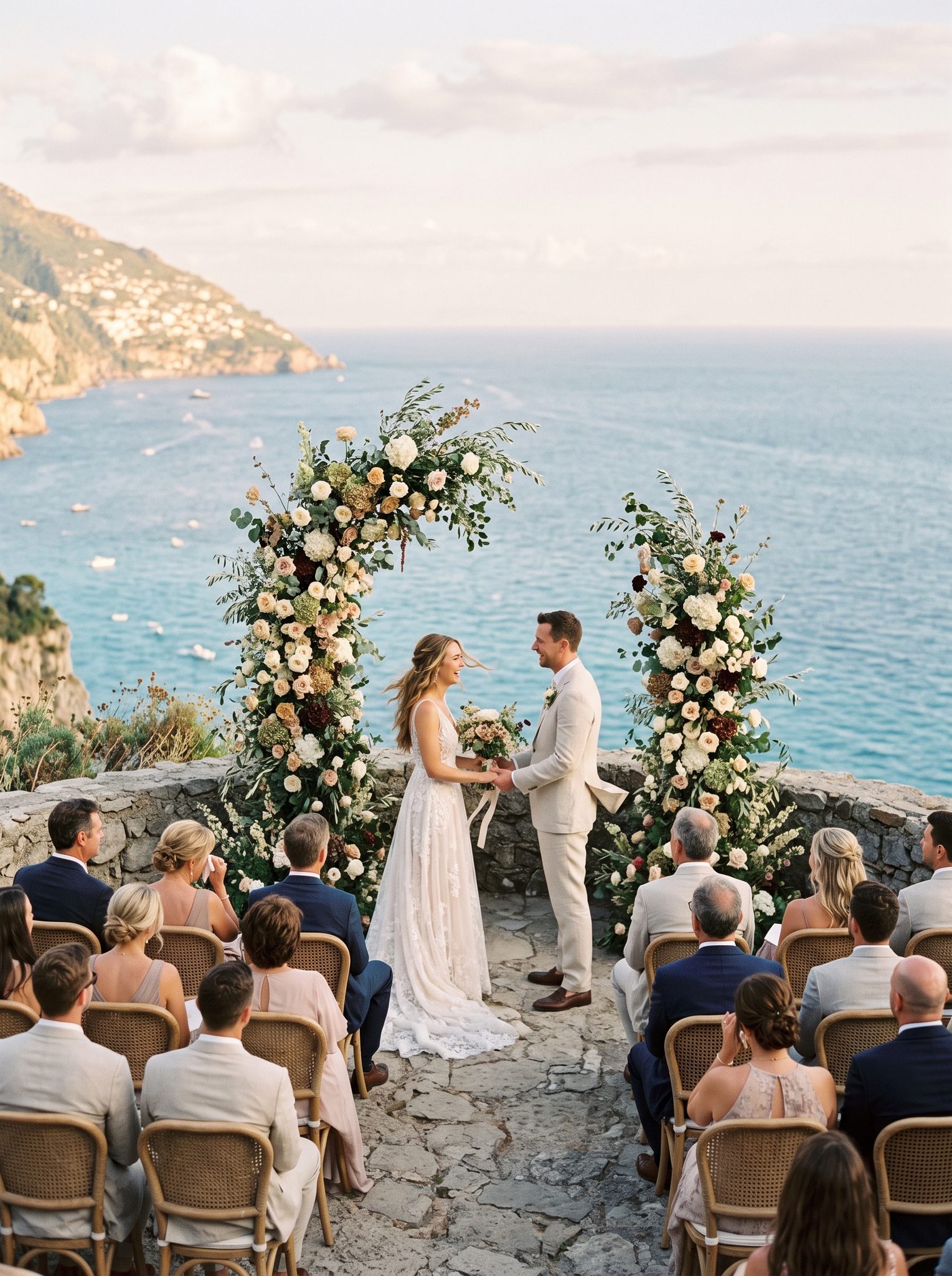 Clifftop wedding ceremony with floral arch overlooking the Mediterranean at golden hour